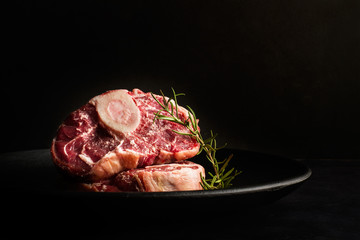 Osobuco carne cruda vista de frente sobre plato negro. Copy space