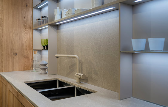 A fragment of the interior of a modern kitchen with a double metal sink and built-in LED lights