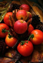 Apple on autumn leaves background, red tomato, onion, pinecone, colorful fruit or vegetable harvesting in fall season, fresh and organic food from nature, copy space