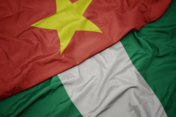 waving colorful flag of nigeria and national flag of vietnam.