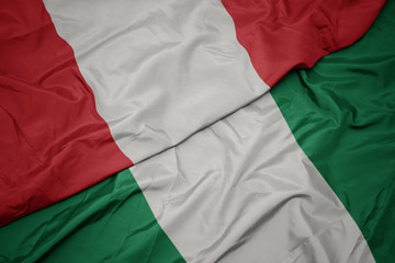 Obraz premium waving colorful flag of nigeria and national flag of peru.