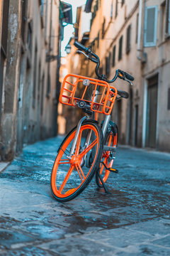 Orange bike parked in the street of Florence historical center, in Italy