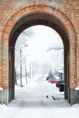 Brick arch in winter city with parking behind it