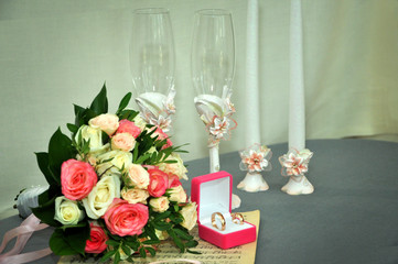 Wedding bouquet, gold wedding rings, glasses, candles are on old notes