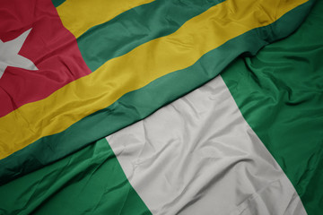 waving colorful flag of nigeria and national flag of togo.