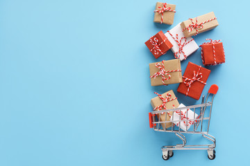 Gift boxes flying out of a shopping cart on black background.