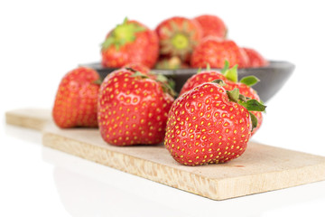 Lot of whole fresh red strawberry in glazed bowl on wooden cutting board isolated on white background
