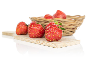 Lot of whole fresh red strawberry on wooden cutting board in round rattan bowl isolated on white background