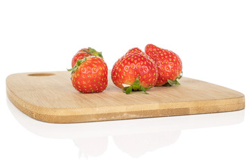 Group of four whole fresh red strawberry on bamboo cutting board isolated on white background