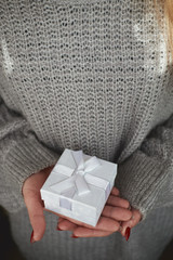 girl with red manicure on nails holds christmas gift boxes woman in warm gray sweater holds in front of herself