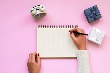 Home office desktop with girl's hand, pen, coffee mug and note on pink background. Copy space on color background. Top view. Flat lay style