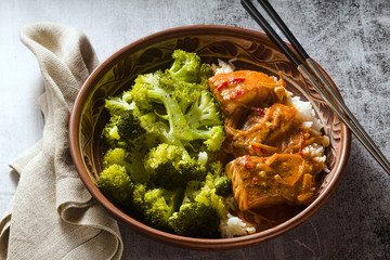 Thai salmon dish in coconut sauce with fresh broccoli and rice in a clay bowl with chopsticks . healthy food with vitamin B5...
