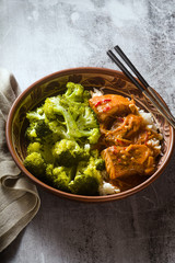 Thai salmon dish in coconut sauce with fresh broccoli and rice in a clay bowl with chopsticks . healthy food with vitamin B5...