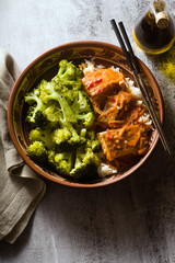Thai salmon dish in coconut sauce with fresh broccoli and rice in a clay bowl with chopsticks . healthy food with vitamin B5...