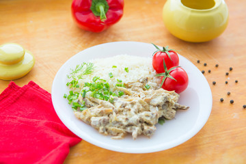 Stewed beef and rice on the white plate on wooden background.