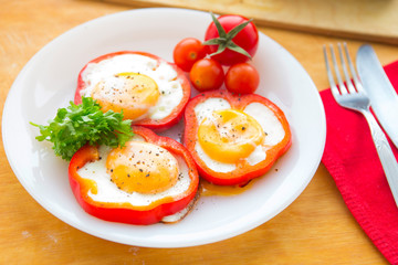 Fried eggs in paprika served on white plate on wooden background