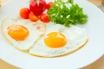 Fried Eggs on a plate on rustic wooden background