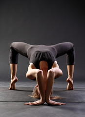 young caucasian girl in black sportswear doing yoga or pilates exercise. Healthy and active lifestyle. Asana practice.