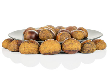 Lot of whole sweet brown chestnut on gray ceramic plate isolated on white background
