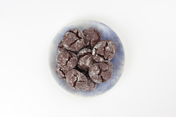 Chocolate crinkle cookies in blue plate, white background. Christmas, recipe concept. Top view, flat lay, copy space