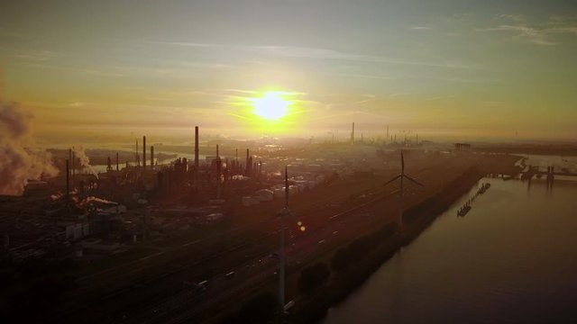 Aerial view of twilight of oil refinery , shot with drone. Oil refinery and Petrochemical plant at dusk . Wind mill visible. Shot in Pernis Rotterdam.