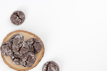 Chocolate crinkle cookies on wooden stand, white background. Christmas, recipe concept. Top view, flat lay, copy space