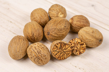 Group of eight whole one half one piece of dry brown nutmeg on white wood