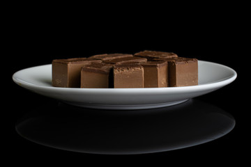 Lot of whole sweet brown viennese nougat on white ceramic plate isolated on black glass