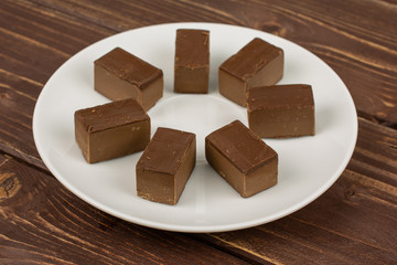 Group of seven whole sweet brown viennese nougat on white ceramic plate on brown wood