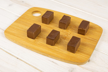 Group of six whole sweet brown viennese nougat on bamboo cutting board on white wood