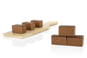 Group of six whole sweet brown viennese nougat on small wooden cutting board isolated on white background