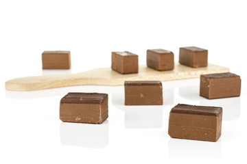 Group of eight whole sweet brown viennese nougat on small wooden cutting board isolated on white background