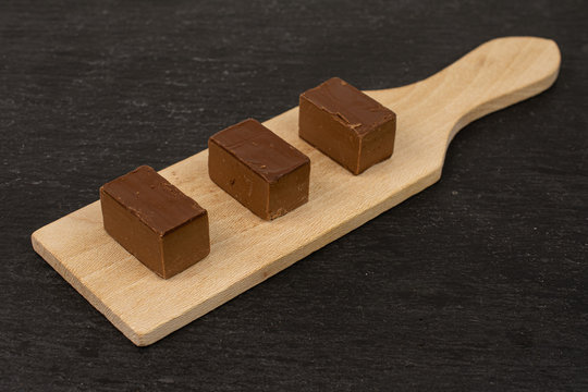Group of three whole sweet brown viennese nougat on small wooden cutting board on grey stone