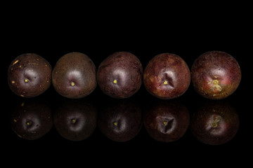 Group of five whole sweet dark purple passion fruit in line isolated on black glass