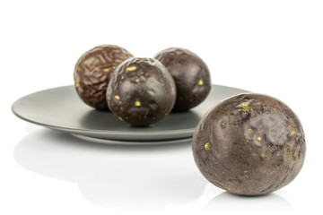 Group of four whole sweet dark purple passion fruit on gray ceramic plate isolated on white background