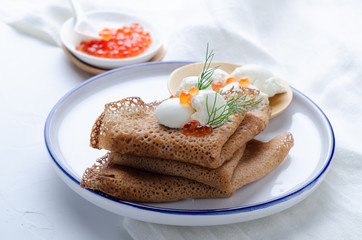 Russian pancakes with red caviar and sour cream.