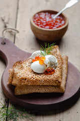 Russian pancakes with red caviar and sour cream.