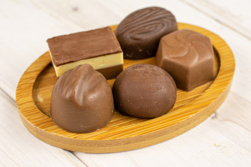 Group of five whole delicious chocolate praline on bamboo coaster on white wood