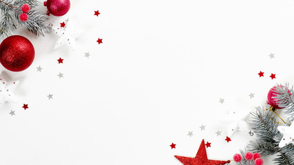 Christmas tree branches with red balls and stars over white background with confetti. Christmas...