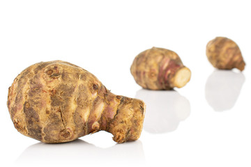 Group of three whole fresh brown jerusalem artichoke in row isolated on white background