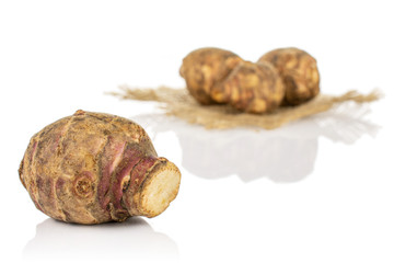 Group of four whole fresh brown jerusalem artichoke on natural sackcloth isolated on white background