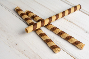 Group of three whole crunchy beige hazelnut rolled wafer biscuit on white wood