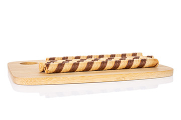 Group of four whole crunchy beige hazelnut rolled wafer biscuit on bamboo cutting board isolated on white background