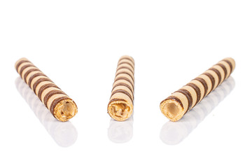 Group of three whole crunchy beige hazelnut rolled wafer biscuit isolated on white background