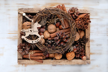 ute horse toy and cones, nuts, cinnamon in wooden box. nature seasonal autumn or winter background, creative concept. rustic scandinavian style. soft focus