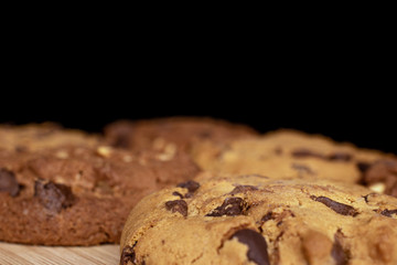 Group of five whole sweet brown cookie on bamboo cutting board isolated on black glass