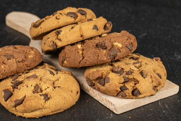Group of six whole sweet brown cookie on wooden cutting board flatlay on grey stone