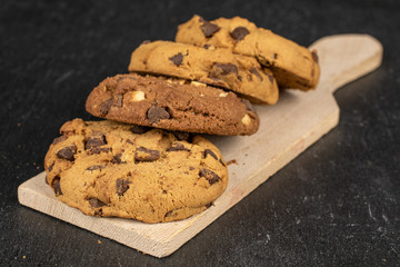 Group of four whole sweet brown cookie on wooden cutting board flatlay on grey stone