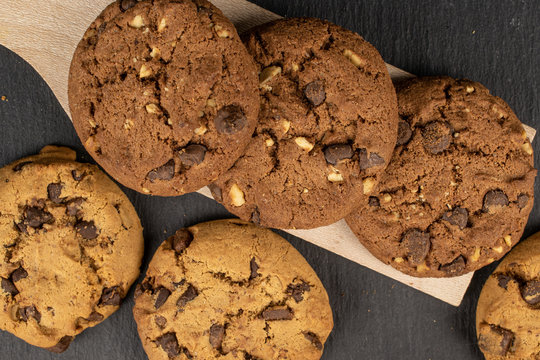 Group of six whole sweet brown cookie on wooden cutting board flatlay on grey stone