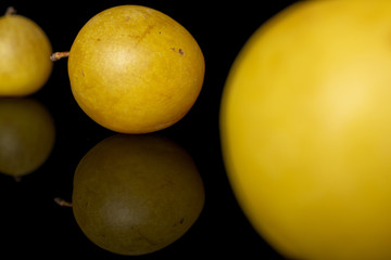 Group of three whole fresh yellow plum isolated on black glass